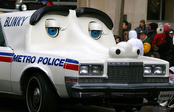 A white police car that has been modified to look like a cartoon car with big eyes and eye browns